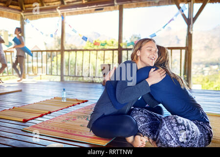 Happy mother and daughter hugging sur tapis de yoga en hut au cours de yoga retreat