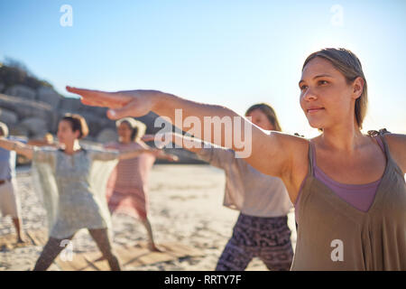 Certain woman practicing warrior 2 poser sur plage ensoleillée au cours de yoga retreat Banque D'Images