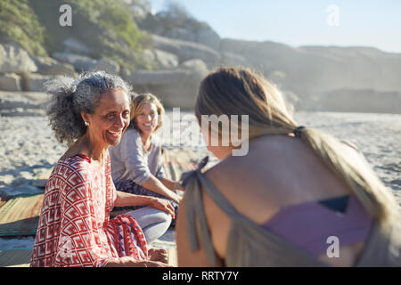 Smiling women friends talking on sunny beach au cours de yoga retreat Banque D'Images