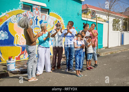 Heureux de célébrer les bénévoles de la communauté urbaine murale peinte sur mur ensoleillé Banque D'Images