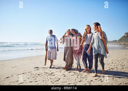 Amis marchant avec un tapis de yoga sur la plage ensoleillée au cours de yoga retreat Banque D'Images