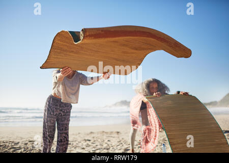 Femme portant un tapis de yoga sur la plage ensoleillée au cours de yoga retreat Banque D'Images