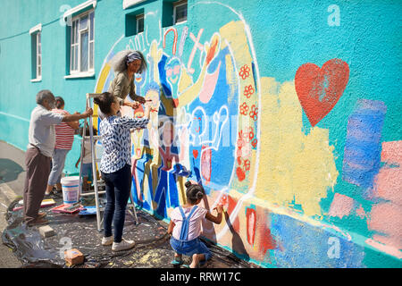 Bénévoles de la communauté peinture murale multicolore sur mur urbain ensoleillé Banque D'Images