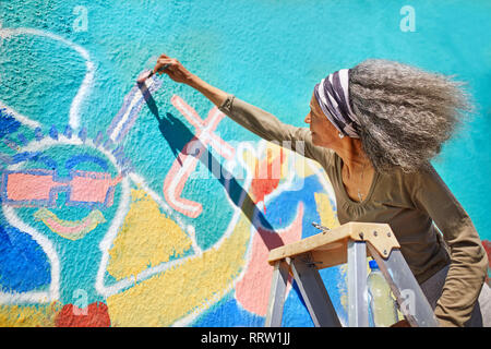 Peinture murale haute femme dynamique sur mur ensoleillé Banque D'Images