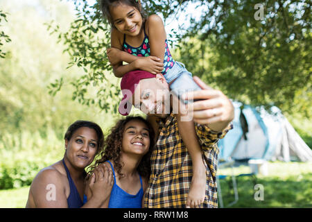 Heureux, affectueux avec la famille en tenant l'appareil photo au téléphone selfies camping Banque D'Images