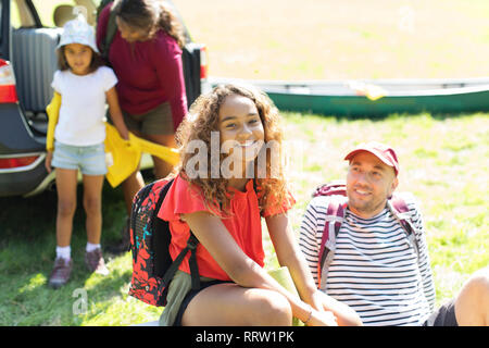 Happy girl Portrait camping en famille, déchargement voiture à field Banque D'Images