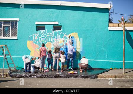 Les bénévoles de la communauté dynamique de peinture murale sur mur urbain ensoleillé Banque D'Images