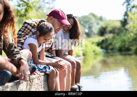 Family sitting au bord de dock riverside Banque D'Images