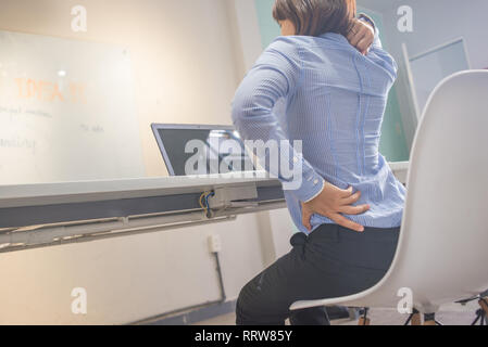 Jeune femme assise avec mal de dos au bureau. Banque D'Images