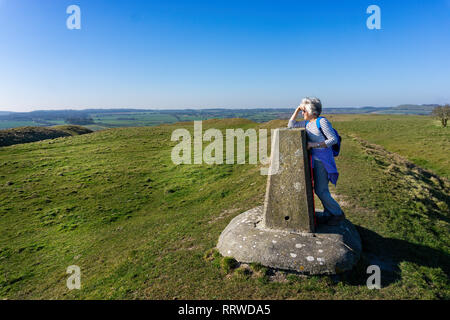 Femme mature très admiratifs de rambler vue depuis un point de triangulation ou trig point sur feuille blanche Hill dans le Wiltshire, UK Banque D'Images