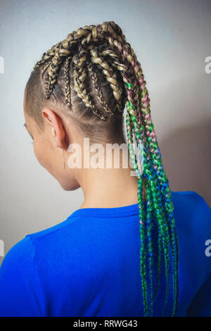 Les femmes de cornrows une femme avec une coupe sur un fond blanc, les tresses serrées dans une queue tressée, matériau artificiel tissé dans ses cheveux Banque D'Images