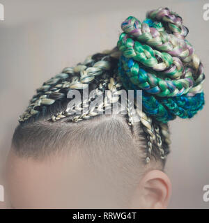 Les femmes de cornrows une femme avec une coupe sur un fond blanc, les tresses serrées dans une queue tressée, matériau artificiel tissé dans ses cheveux Banque D'Images