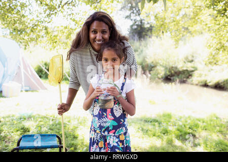 Heureux Portrait mère et fille avec filet de pêche et poissons dans le bocal de camping Banque D'Images