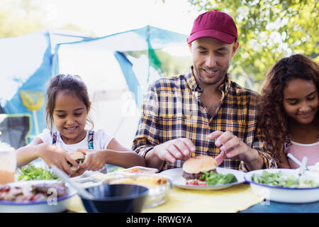 Père et filles bénéficiant d'hamburger déjeuner au camping Banque D'Images