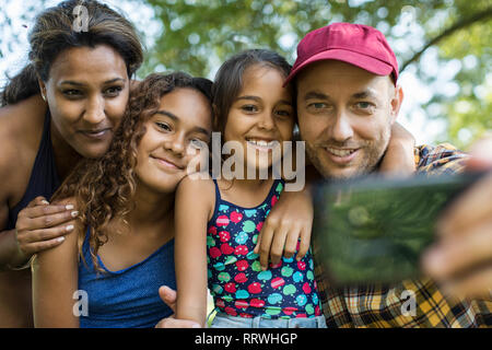 Famille heureuse en tenant avec selfies téléphone appareil photo Banque D'Images