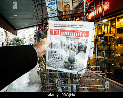 PARIS, FRANCE - DEC 10, 2018 : stand kiosque Kiosque presse vente mâle avec l'achat de main dernières l'humanite edition avec gilets jaunes Yellow Jackets mouvements sur capot avant Banque D'Images