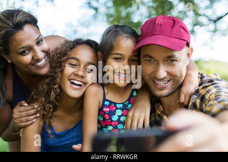 Famille heureuse en tenant avec selfies téléphone appareil photo Banque D'Images