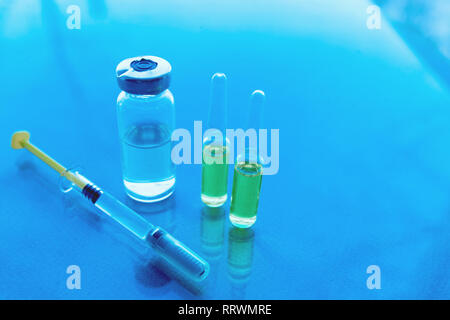 Les seringues, flacons de médicaments sur un fond bleu. Concept de vaccination Banque D'Images