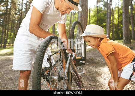 Père et fils réparer un vélo dans le parc. Banque D'Images