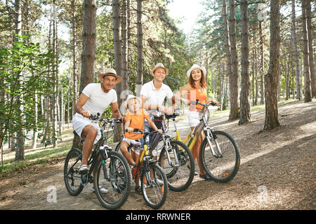 Famille heureuse sur les bicyclettes pour une promenade en parc. Banque D'Images