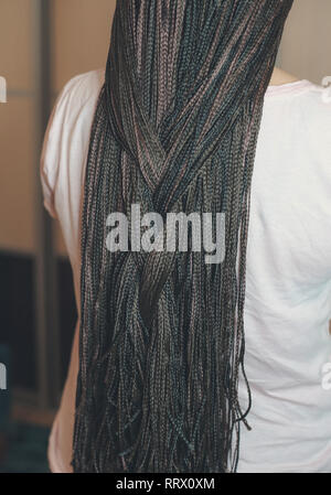 Les femmes de cornrows une femme avec une coupe sur un fond blanc, les tresses serrées dans une queue tressée, matériau artificiel tissé dans ses cheveux Banque D'Images