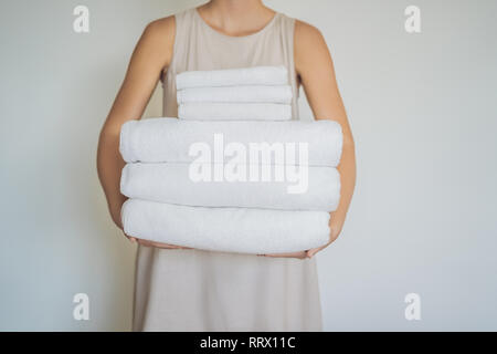 Une femme tient une pile de serviettes blanches. Concept de service dans les hôtels, blanchisserie, spa Banque D'Images