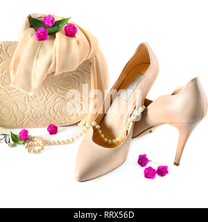 Chaussures femme élégante, petit sac à main, foulard au cou et de perle isolé sur fond blanc. Un ensemble d'accessoires en beige pastel. Banque D'Images