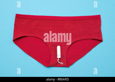 Tampon blanc sur un pantalon rouge sur fond de couleur. concept de la femme pendant les règles d'hygiène Banque D'Images