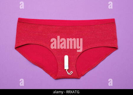 Tampon blanc sur un pantalon rouge sur fond de couleur. concept de la femme pendant les règles d'hygiène Banque D'Images