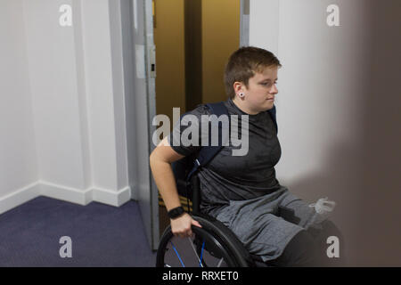 Jeune femme en fauteuil roulant de sortir de l'ascenseur Banque D'Images