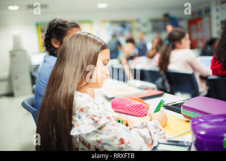 Junior high school student girl doing homework at desk in classroom Banque D'Images