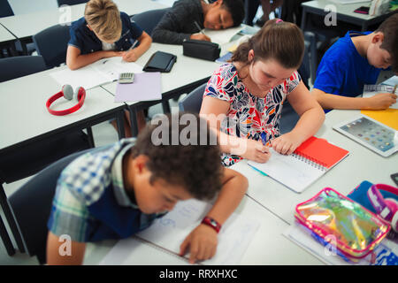 Des élèves du premier cycle du secondaire à faire leurs devoirs à un bureau dans la salle de classe Banque D'Images