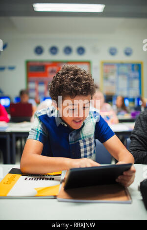 Garçon junior high school student using digital tablet in classroom Banque D'Images