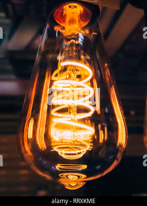 Lampe en verre clair brillant lumineux en forme de poire de près. Edison eclairage lampe rétro arrière-plan sombre. Ampoule à incandescence anciennes. Banque D'Images