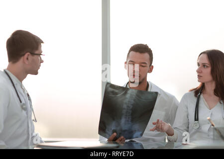 Les médecins de discuter de la x-ray de la patient assis à la table Banque D'Images