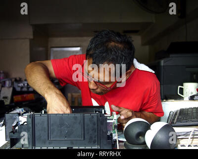 ANTIPOLO CITY, PHILIPPINES - le 21 février 2019 : Un technicien à un atelier de réparation électrique fixe une imprimante de l'ordinateur d'un client. Banque D'Images