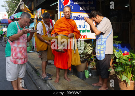 Les commerçants locaux à Thonburi, Bangkok, Thaïlande, en priant pour un moine bouddhiste au cours de sa ronde alms matin traditionnel Banque D'Images