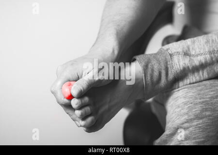 Homme Causian détient les mains pour ses pieds douloureux, la douleur en pouces. La photographie en noir et blanc. Couleur rouge est domaine de la douleur Banque D'Images