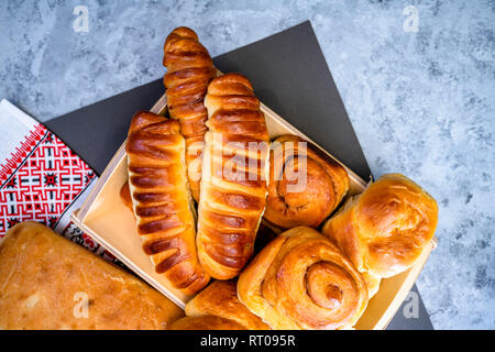 Délicieux délicieux petits pains cuits émaillés ruddy, tartes et pâtisseries à la cannelle et diverses garnitures, fabriqué à partir de farine biologique premium, disposés sur un woo Banque D'Images