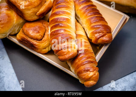 Délicieux délicieux petits pains cuits émaillés ruddy, tartes et pâtisseries à la cannelle et diverses garnitures, fabriqué à partir de farine biologique premium, disposés sur un woo Banque D'Images