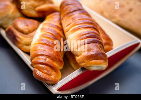 Délicieux délicieux petits pains cuits émaillés ruddy, tartes et pâtisseries à la cannelle et diverses garnitures, fabriqué à partir de farine biologique premium, disposés sur un woo Banque D'Images