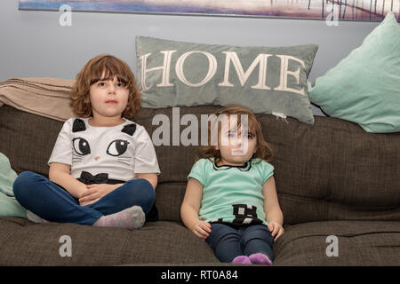 Deux soeurs à la maison à regarder la TV sur le canapé. Banque D'Images