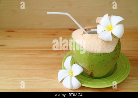 Les jeunes avec de la noix de coco fraîche paille blanc et fleurs Plumeria servi sur plaque verte prêt à boire Banque D'Images