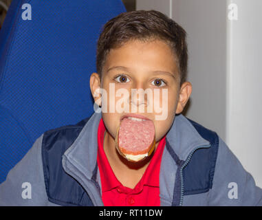 Drôle de garçon de 12 ans avec sandwich saucisse dans sa bouche Banque D'Images