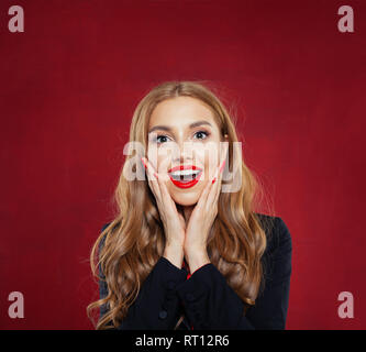 Surpris femme avec bouche ouverte sur fond rouge. Happy girl having fun. Des émotions positives Banque D'Images