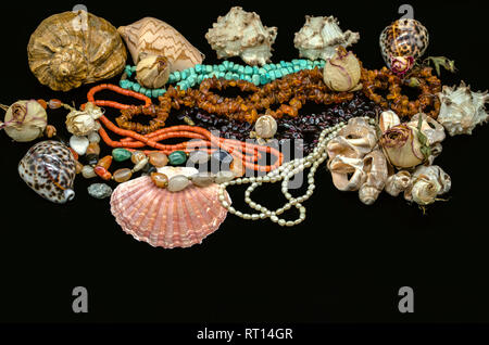 Perles de turquoise, corail rouge, ambre, grenat, pierre agate multicolore, perles parmi les divers coquillages et sécher les bourgeons sur un fond noir Banque D'Images