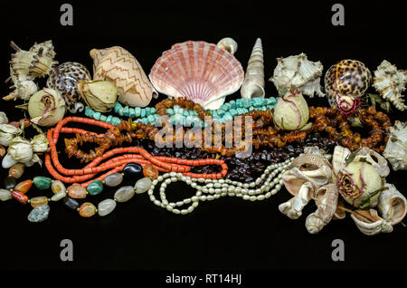 Perles de turquoise, corail rouge, ambre, grenat, pierre agate multicolore, perles parmi les divers coquillages et sécher les bourgeons sur un fond noir Banque D'Images