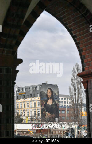 Berlin, Allemagne. Feb 26, 2019. Une copie grand format de Léonard de Vinci la Joconde est peinte sur une façade de maison à l'East Side Gallery. De concert avec les artistes, réservoir Weisse Seite et fixer77, l'artiste berlinois Die collective Dixons a peint une réplique de la Joconde dans une taille de 16,30 et 10,60 mètres sur le pare-feu d'un hotel à Mühlenstraße en face de l'East Side Gallery. Credit : Jens Kalaene Zentralbild-/dpa/dpa/Alamy Live News Banque D'Images