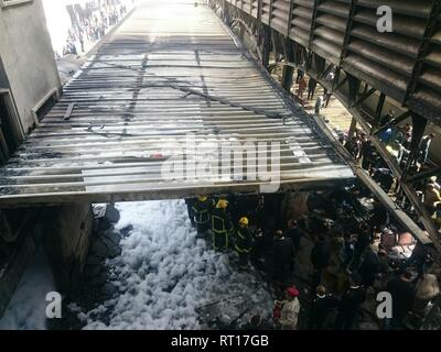 Le Caire, Égypte. Feb 27, 2019. Les secouristes se tiennent près d'un wagon a brûlé après un incendie a causé morts et blessés à la gare principale, au Caire. Incendie a éclaté après qu'un train est entré à la station, dépassant la vitesse et entre en collision avec le tampon s'arrêter. Credit : Ahmed Abd Elfatah/dpa/Alamy Live News Banque D'Images