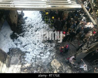 Le Caire, Égypte. Feb 27, 2019. Les secouristes se tiennent près d'un wagon a brûlé après un incendie a causé morts et blessés à la gare principale, au Caire. Incendie a éclaté après qu'un train est entré à la station, dépassant la vitesse et entre en collision avec le tampon s'arrêter. Credit : Ahmed Abd Elfatah/dpa/Alamy Live News Banque D'Images